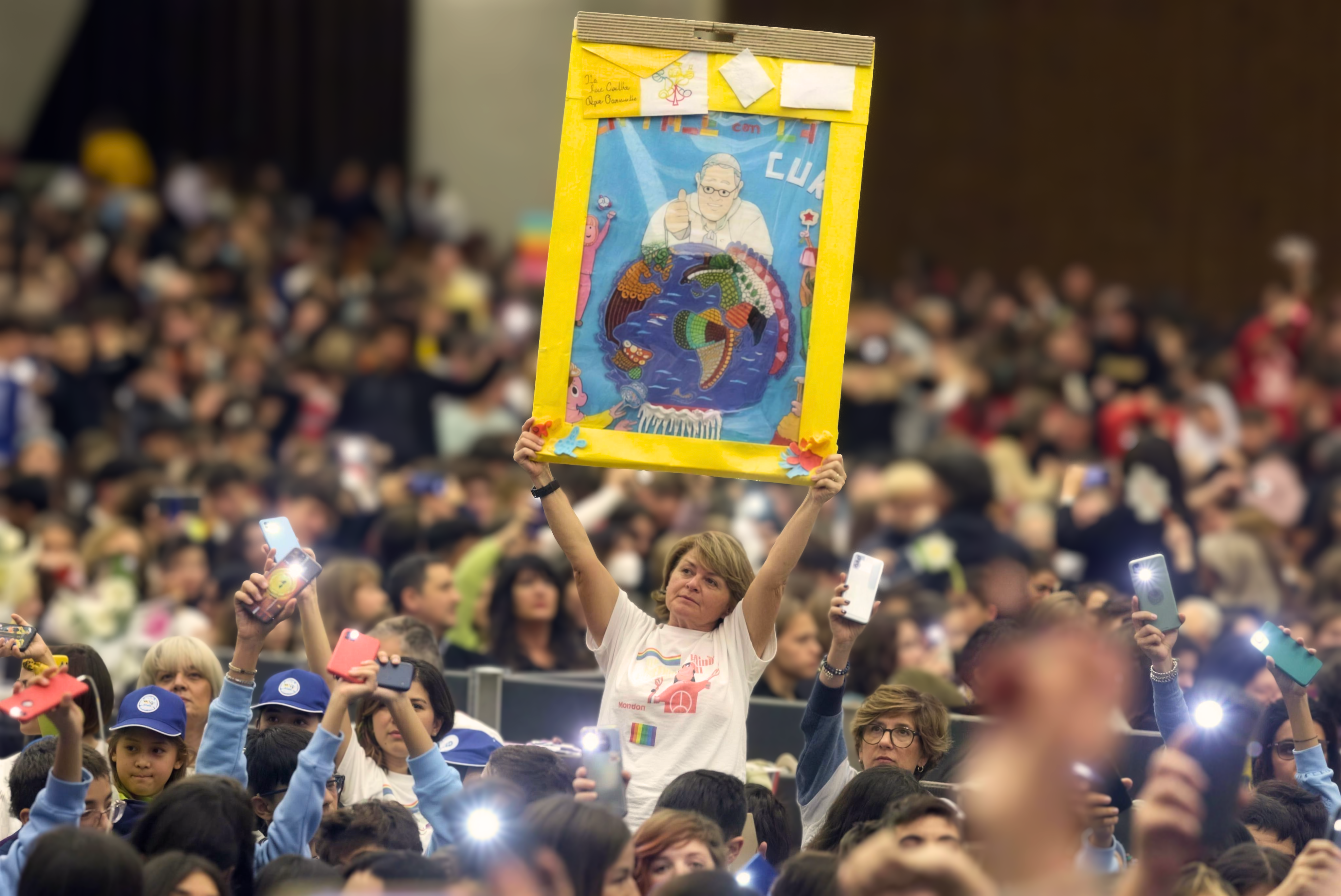 Maestra Agnese solleva un lavoro realizzato con la classe durante un grande incontro